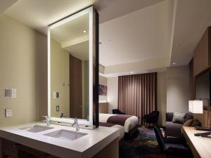 a hotel room with a bathroom with a bed and a mirror at Millennium Mitsui Garden Hotel Tokyo - Ginza in Tokyo