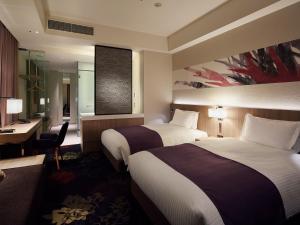 a hotel room with two beds and a desk at Millennium Mitsui Garden Hotel Tokyo - Ginza in Tokyo