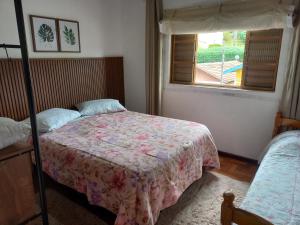 a bedroom with two beds and a window at Casa Recanto in Campos do Jordão