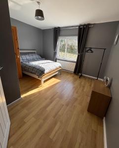 a bedroom with a bed and a wooden floor at Christinas Cottage Downpatrick in Raholp