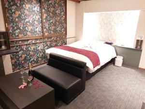 松本市にあるHotel Lara Cielのベッドルーム1室(ベッド1台、ベンチ、テーブル付)