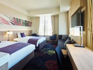 a hotel room with two beds and a desk at Millennium Mitsui Garden Hotel Tokyo - Ginza in Tokyo