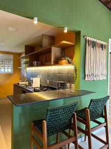a kitchen with green walls and a counter with chairs at Casa Airton 33 in Extremóz