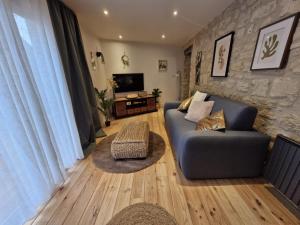 a living room with a blue couch and a tv at La petite champêtre in Bouconville-Vauclair
