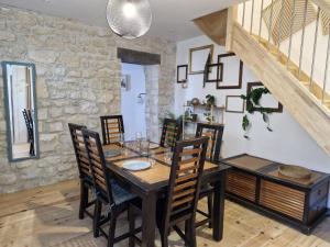 a dining room with a table and chairs and a stone wall at La petite champêtre in Bouconville-Vauclair