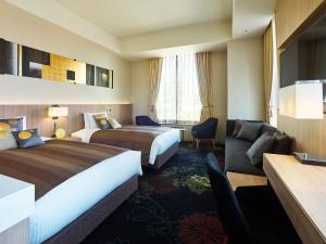 a hotel room with two beds and a couch at Millennium Mitsui Garden Hotel Tokyo - Ginza in Tokyo
