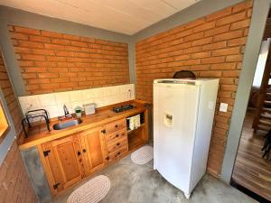 a kitchen with a white refrigerator and wooden cabinets at Chalé Jacarandá - Hidro - Wifi e mais in Sapucaí-Mirim