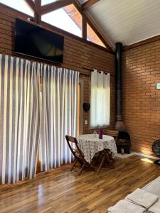 a living room with a table and a fireplace at Chalé Jacarandá - Hidro - Wifi e mais in Sapucaí-Mirim