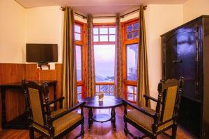 a dining room with a table and two chairs and a window at Treebo The Alpine Heritage Residency in Shimla