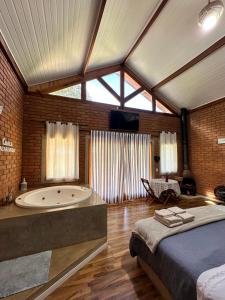 a bedroom with a large bed and a bath tub at Chalé Jacarandá - Hidro - Wifi e mais in Sapucaí-Mirim
