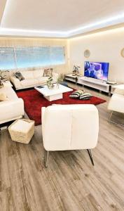 a living room with white furniture and a red rug at Maison Ali in Ville Nouvelle