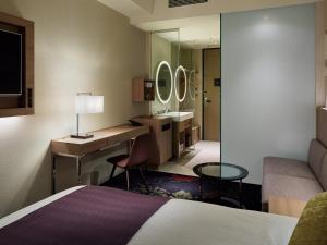 a hotel room with a bed and a desk and a sink at Millennium Mitsui Garden Hotel Tokyo - Ginza in Tokyo