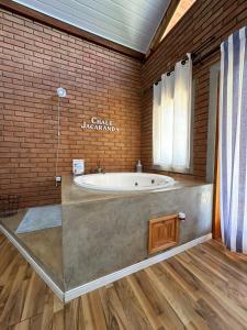 a bathroom with a tub in a brick wall at Chalé Jacarandá - Hidro - Wifi e mais in Sapucaí-Mirim