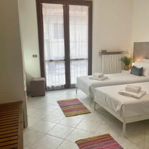 two beds in a room with two windows at Bnbook Residenza Vespucci in Sedriano