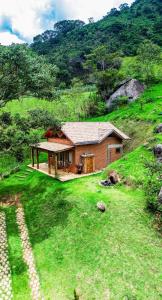 a small house on a hill with a green field at Chalé Jacarandá - Hidro - Wifi e mais in Sapucaí-Mirim