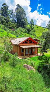 a house on top of a grassy hill at Chalé Jacarandá - Hidro - Wifi e mais in Sapucaí-Mirim