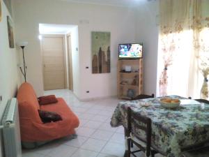 a living room with a table and a chair and a television at Appartamento Vallone Petrara in Reggio di Calabria