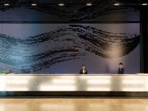 two people standing in front of a wall with a large painting at Millennium Mitsui Garden Hotel Tokyo - Ginza in Tokyo