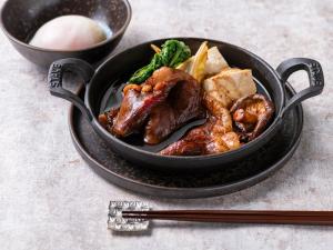 a black bowl of food with meat and vegetables at Millennium Mitsui Garden Hotel Tokyo - Ginza in Tokyo