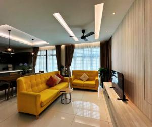 a living room with a yellow couch and a tv at Luxury 5BR stay walk to beach & Night market fun in Batu Ferringhi