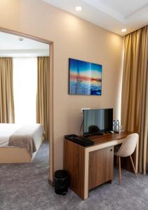 ein Hotelzimmer mit Bett und Schreibtisch mit Fernseher in der Unterkunft Aniko Hotel in Batumi