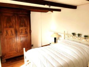 a bedroom with a white bed and a wooden door at Chez Tata Célestine in Castelnau-Pégayrols