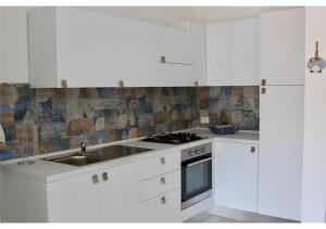 a white kitchen with a sink and a stove at Marina29- Appartamento C in Castelsardo