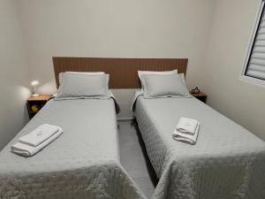 two beds in a room with towels on them at Casa do Lago da Dinda 2 in Espirito Santo Do Pinhal