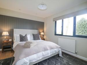 une chambre avec un lit blanc avec des serviettes dessus dans l'établissement Holm Oaks Cottage, à Godalming