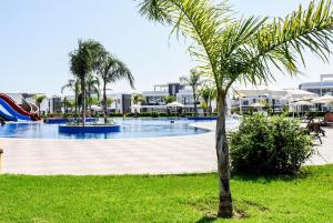 a palm tree next to a swimming pool with a slide at Luxury Two-Bedroom Apartment at Four Seasons Life 2 16-B in Boghaz