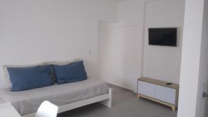 a room with a bed with blue pillows and a television at Frente al mar in Pinamar