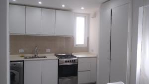 a white kitchen with a stove and a sink at Frente al mar in Pinamar