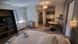 a bedroom with a bed and a table and a kitchen at La Marie Galante Appart'Hotel in Saint-Georges-dʼOléron