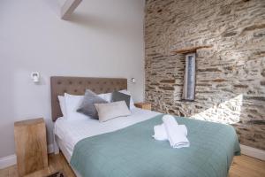 een slaapkamer met een bed en een stenen muur bij Granary Cottage with hot tub on organic farmland in Lampeter