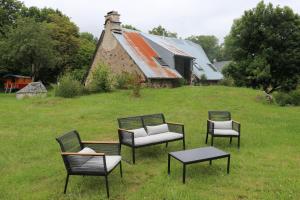 four chairs and a table in a field with a barn at La Fermette de Loucheyre in Saint-Amandin