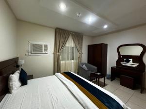 哈伊勒Hotel alras line Suites的带一张大床和一把椅子的卧室