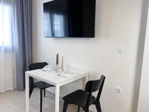 Cheap, Near Beach & Easy Parking - by Solstad في كافالا: طاولة بيضاء مع كرسيين وتلفزيون على الحائط