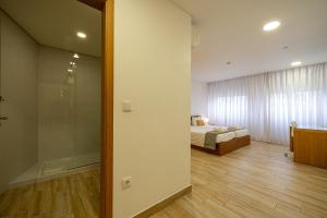 a room with a bed and a glass door to a bedroom at Central Suites in São João da Madeira
