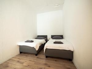 two beds in a room with white walls and wooden floors at Zentrale Unterkunft Nähe Hbf in Koblenz