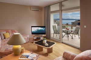 a living room with a television and a balcony at Palmaja in Kaštela +35 photos