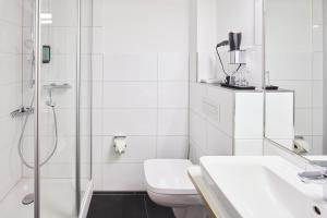 a white bathroom with a toilet and a shower at Hotel & Restaurant zum Ritter in Attendorn