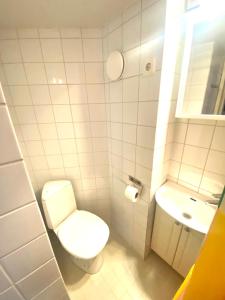 a white bathroom with a toilet and a sink at Pink Gem, Kamppi in Helsinki