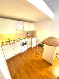 a kitchen with white cabinets and a wooden floor at Pink Gem, Kamppi in Helsinki +4 photos