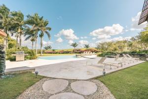 a swimming pool with benches and palm trees at Wonderful 1-BR apartment at Casa de Campo in El Infiernito +6 photos