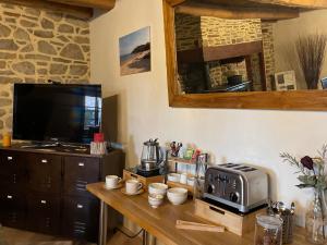 a kitchen with a table with a microwave and a television at Le Haut Pont de la Baie in Mont-Dol