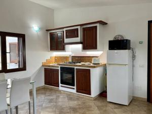 a kitchen with wooden cabinets and a white refrigerator at Villetta Saba in Olbia