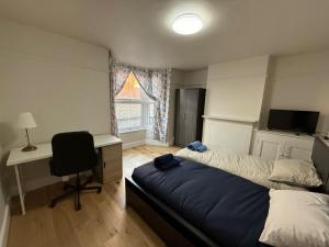 Un dormitorio con dos camas y un escritorio y una ventana. en Flourish House, en Gravesend