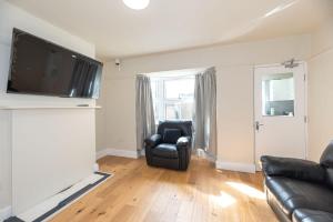 sala de estar con silla de cuero negro y TV en Flourish House, en Gravesend