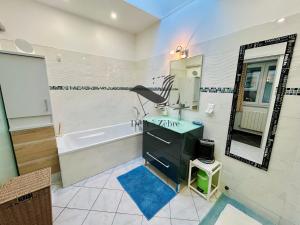 ein Badezimmer mit Waschbecken, Badewanne und Spiegel in der Unterkunft Le Ferney - Proche du centre-ville et des thermes in Rochefort + 29 Fotos