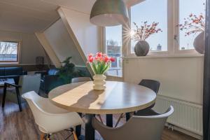 een eettafel met een vaas met bloemen erop bij Appartement Zilt in Hollum